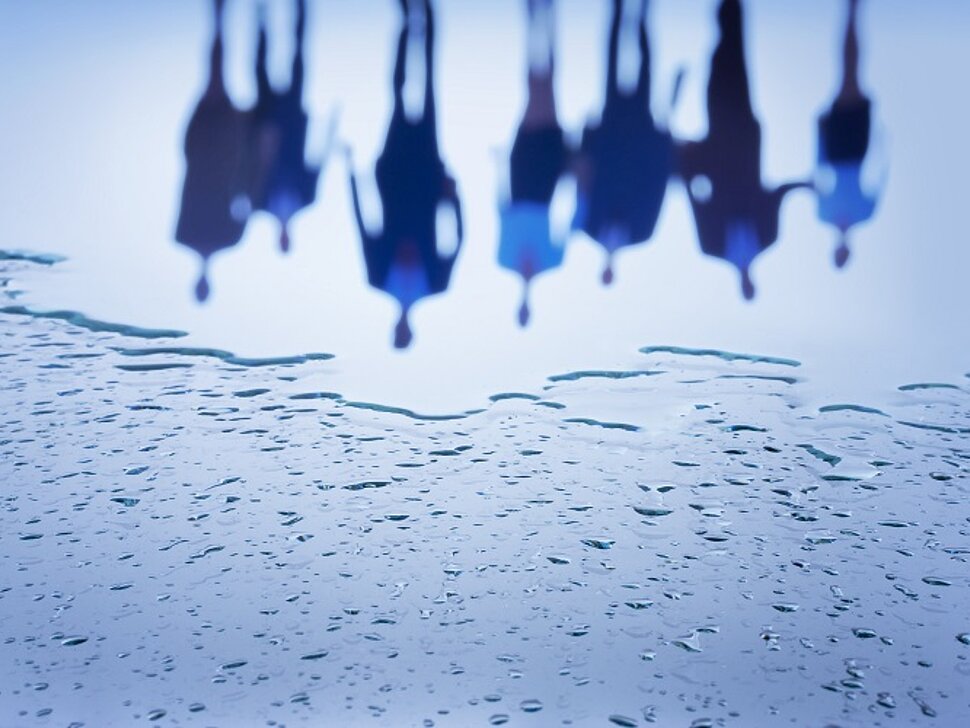 Group,Of,People,Reflecting,In,The,Wet,Glass,Surface,Covered